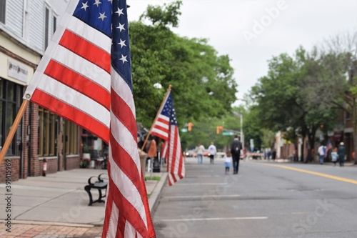 Fototapeta Naklejka Na Ścianę i Meble -  People Walk at at an American Small Town Street Decorated with USA Flags
