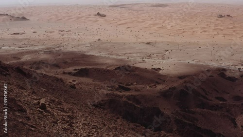 Peeking over the mountain cliff of Sharjah Mleiha, overlooking the sand dunes -aerial photo