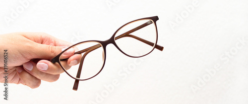 human hand holding modern glasses on white background. Vision concept. Way to improve eyesight.