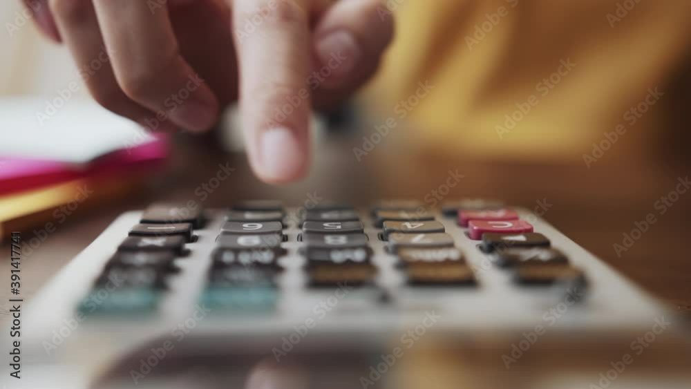 Hand press calculator to calculate income expenses and plans for spending money on home office.