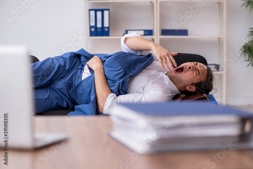 Young male employee sleeping in the office on chairs