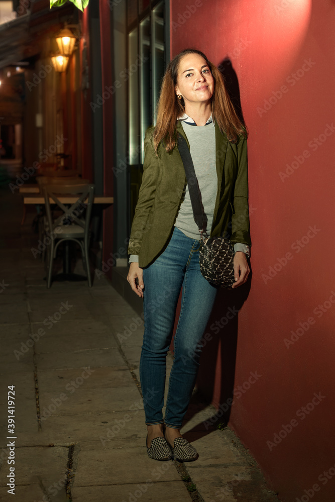 Woman standing leaning on a red wall, outdoors. Woman standing leaning on a red wall, outdoors.