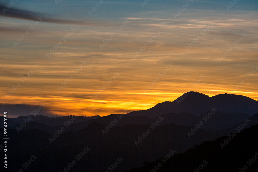 dramatic sunset landscape of the caribbean mountains of the dominican republic with orange clouds and blue sky.