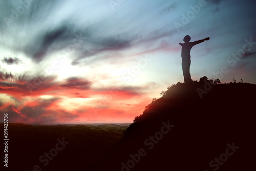 Silhouette of businessman raised hands and praying to god