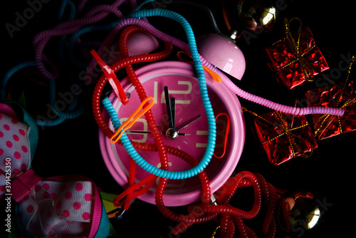 Pink alarm clock with little gift box, colorful knick-knacks, and tie