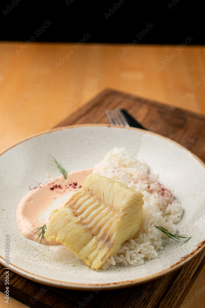White fish fillet, roast with golden crust, laying on a pile of boiled rice, close up White fish fillet, roast with golden crust, laying on a pile of boiled rice, close up
