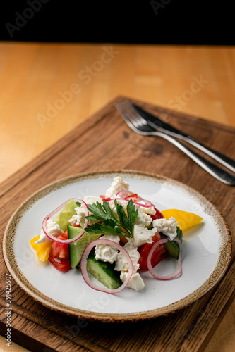 Vegetable salad with crumbled feta cheese on wooden table in greek restaurant