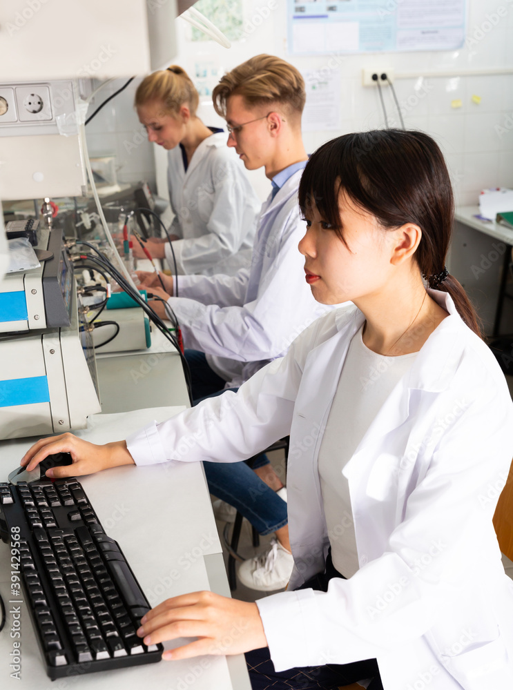 Obraz premium Young Caucasian and Asian students engaged in research at chemical lab