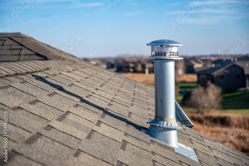 Foto side view of a Galvanized metal chimney exhaust on  asphalt roof with a rain cap