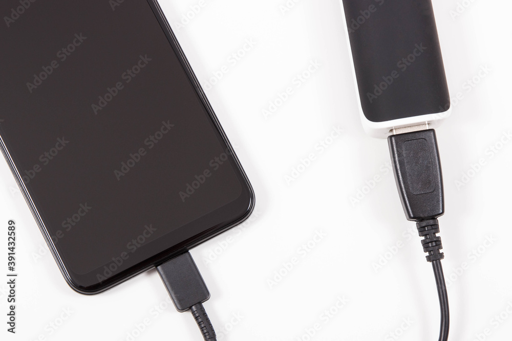Smartphone with connected plug of powerbank. Telephone charging