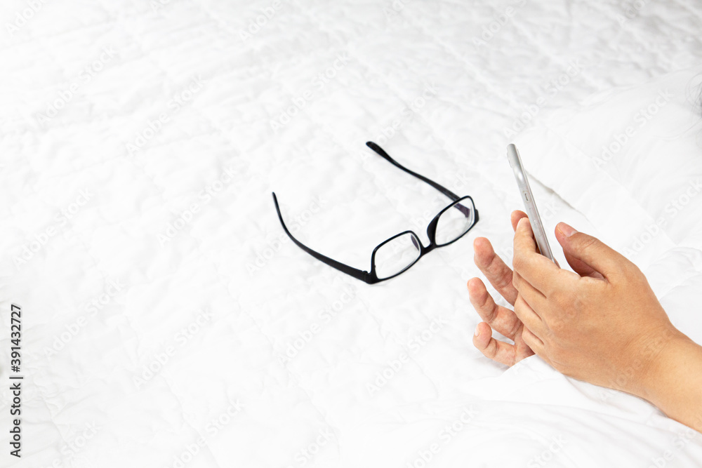 Hands lying in bed and using a smartphone
