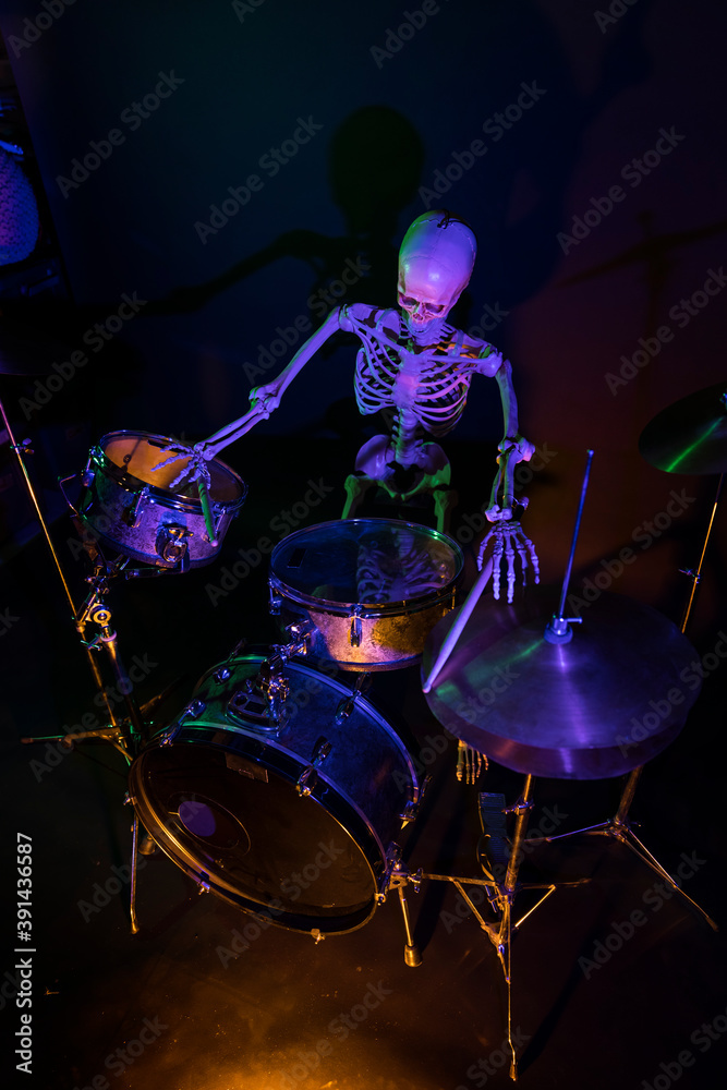 Top down view of skeleton playing drum set on black background