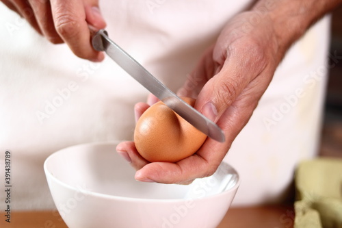 Cracking egg. Making mayonnaise with a wooden spoon.
