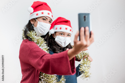 Young family wear christmas hat and face mask having video call with smart phone.