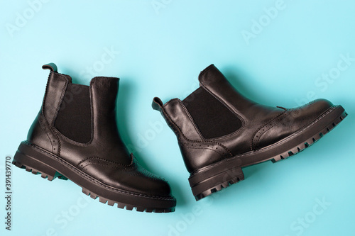 A black autumn boots on blue background, view from above