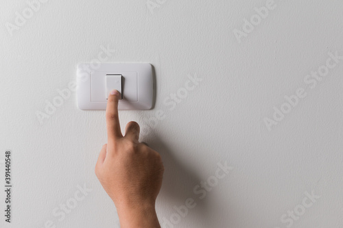 Earth Hour, Close up male hand turn off the light to saving electrical energy. Finger pushing light switch turn on or off. White switch with copy space at home.