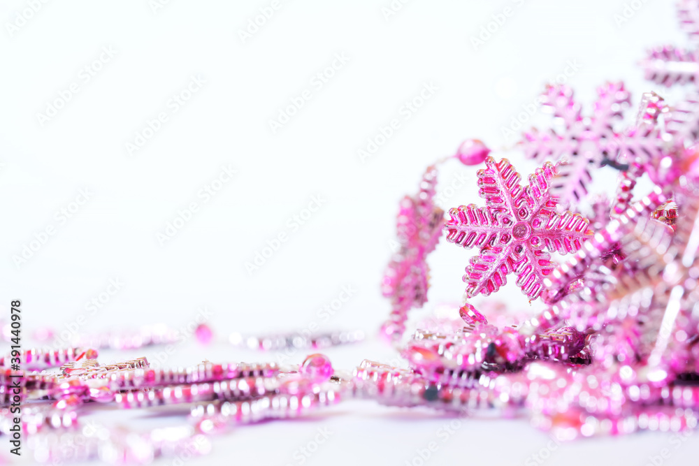 Vintage pink Christmas and New Year tinsel in the form of snowflakes on a white background. Blank for a banner. Bokeh and shallow depth of field.