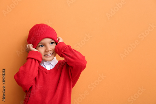 Cute African-American boy in warm hat on color background © Pixel-Shot