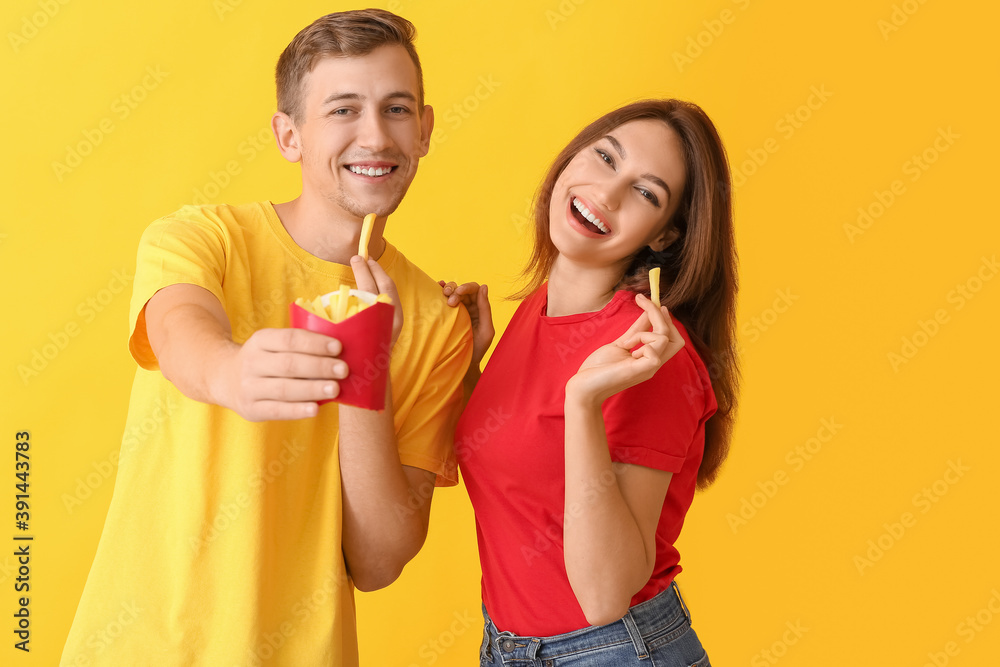 Young couple with french fries on color background Young couple with french fries on color background