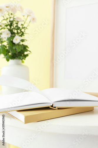 Books and vase with flowers on table in room