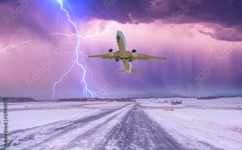 Lightning strikes between stormy clouds - Commercical white airplane take-off runway the (ice) snow-covered airport