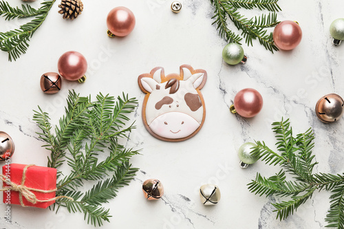 Tasty cookie in shape of bull and Christmas decor on light background