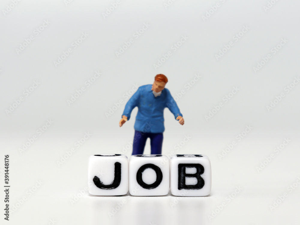 The miniature man standing behind the JOB word cube. The concept of job shortages.
The miniature man standing behind the JOB word cube. The concept of job shortages.