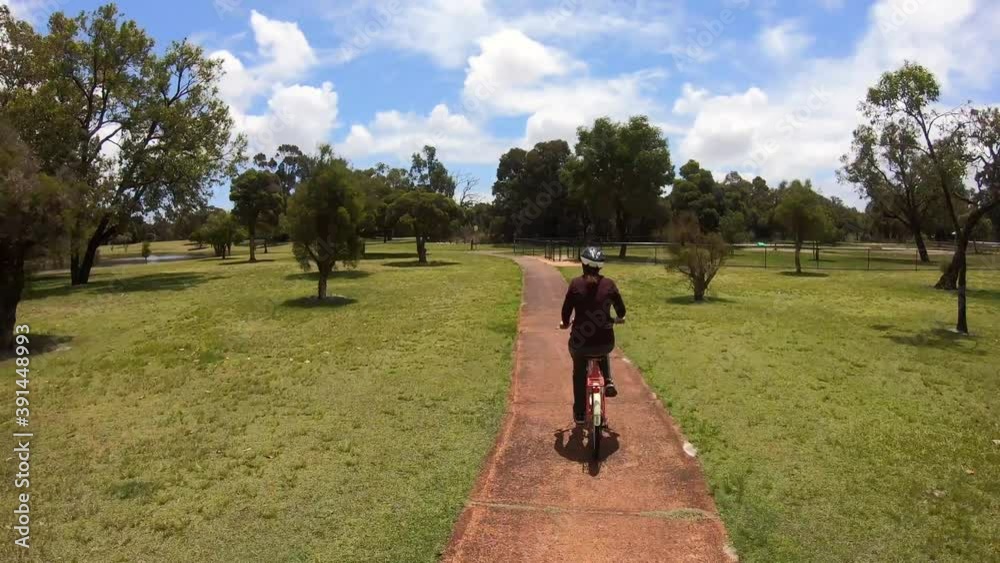 Hyperlapse - Rear view of Adult woman cycling on a bicycle in the park Hyperlapse - Rear view of Adult woman cycling on a bicycle in the park