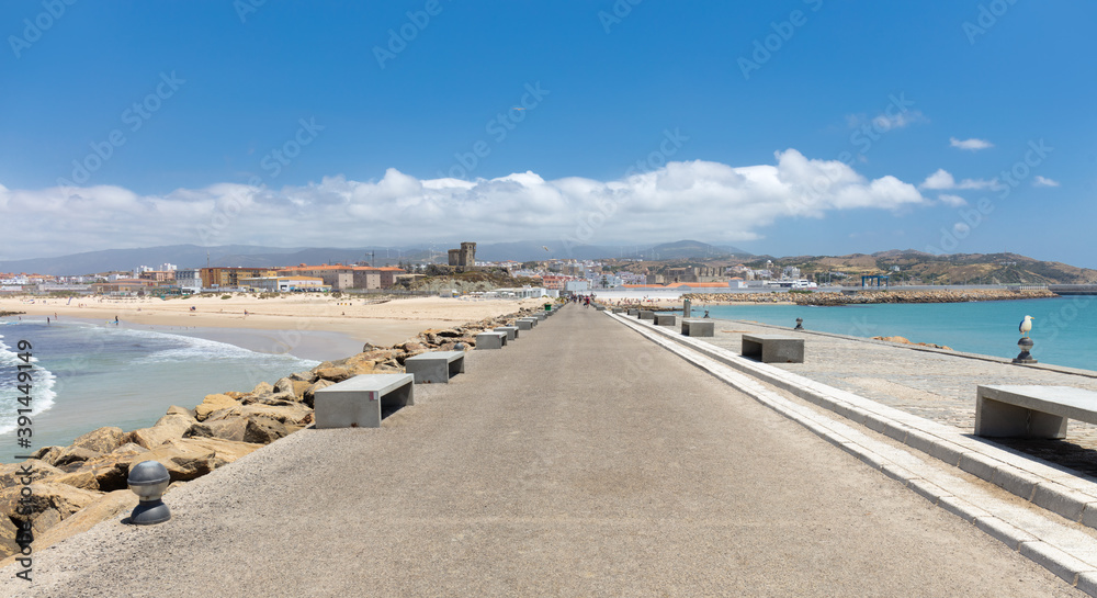 A promenade on the embankment from the fortress to the city of Tarifa in southern Spain in Andalusia in summer. There is a blue sky with sunshine. The beach is on the left.