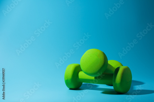 fitness dumbbells on a blue background with a hard shadow
