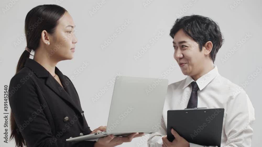 Young Asian man and woman coworkers enthusiastically discuss a successful business concept Young Asian man and woman coworkers enthusiastically discuss a successful business concept