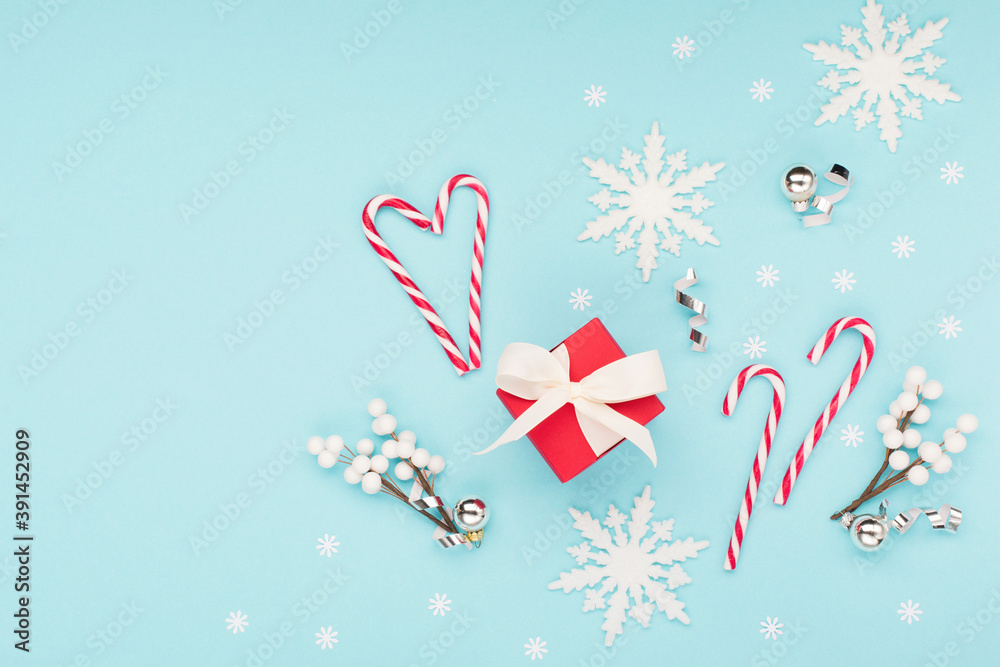 Christmas or winter holiday composition. Card with snowflakes and red gift box on pastel blue background.