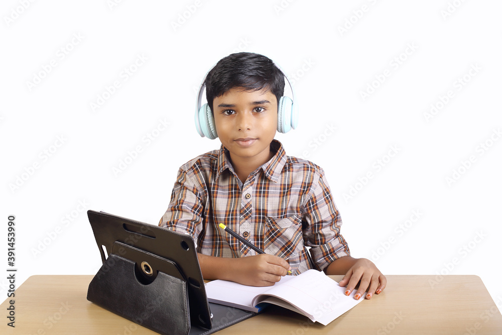 Indian little boy using digital tablet while attending the online classes at home Indian little boy using digital tablet while attending the online classes at home