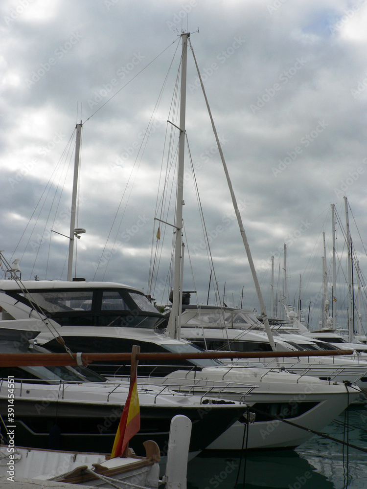 Boats in a yacht club in the Mediterranean sea, island of Mallorca, Spain. Yachts moored in the port on a cloudy day. Boats in a yacht club in the Mediterranean sea, island of Mallorca, Spain. Yachts moored in the port on a cloudy day.