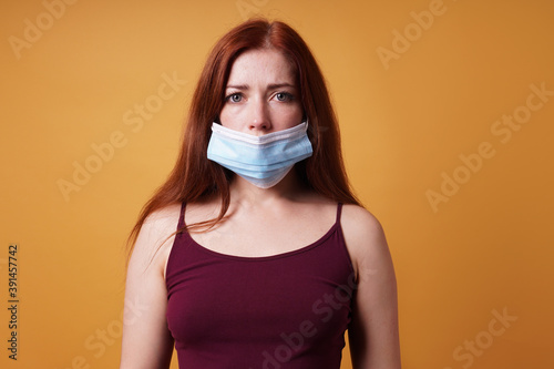 young woman wearing medical face mask wrong leaving nose uncovered - improper use of protective corona coronavirus covid mask photo
