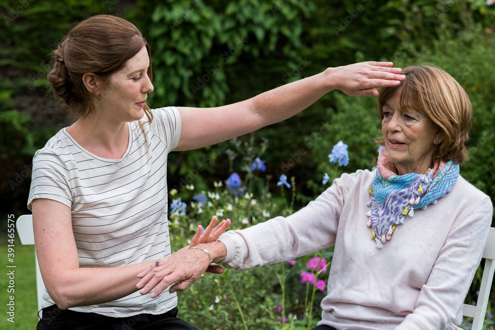 Reiki therapist with a client in a therapy session touching meridian points on the body. Reiki therapist with a client in a therapy session touching meridian points on the body.
