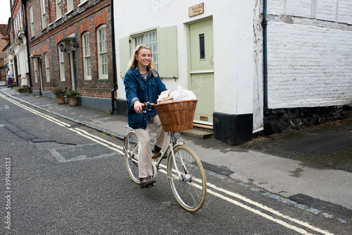 Young blond woman cycling down a village street. photo