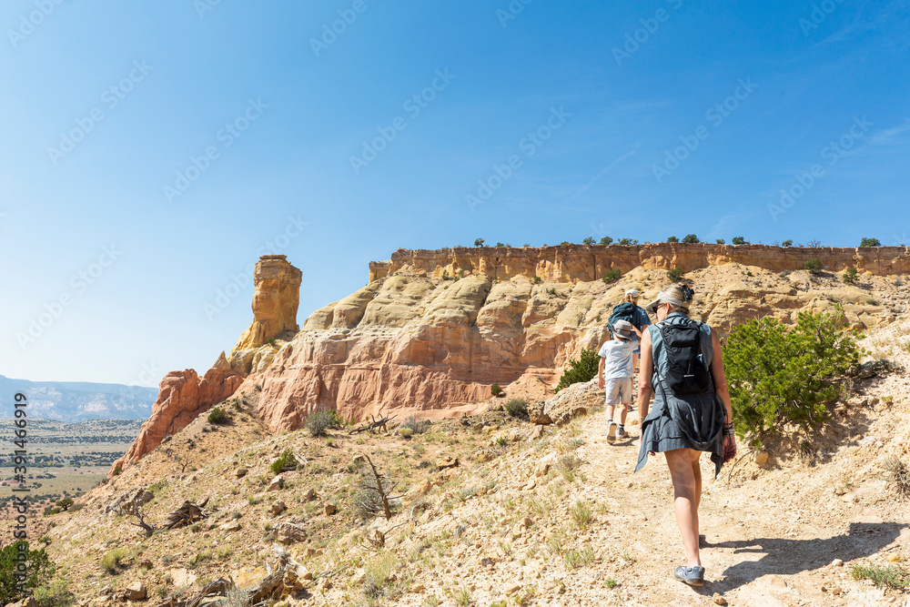 Three people, family hiking on a trail through a protected canyon landscape Three people, family hiking on a trail through a protected canyon landscape