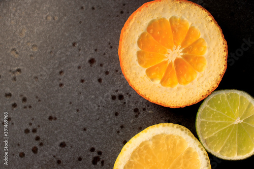 Plate with citrus fresh fruit tangerines with leaves, lemon, lime orange on a dark round plate on a concrete background . vitamins, close-up © Dyukareva Olga