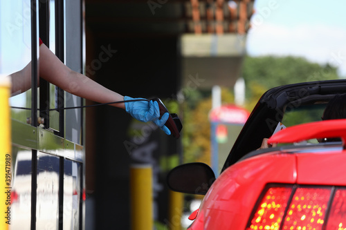 Hand in protective glove holds payment terminal and hands it to driver in car. Safe service in coronavirus pandemic concept photo