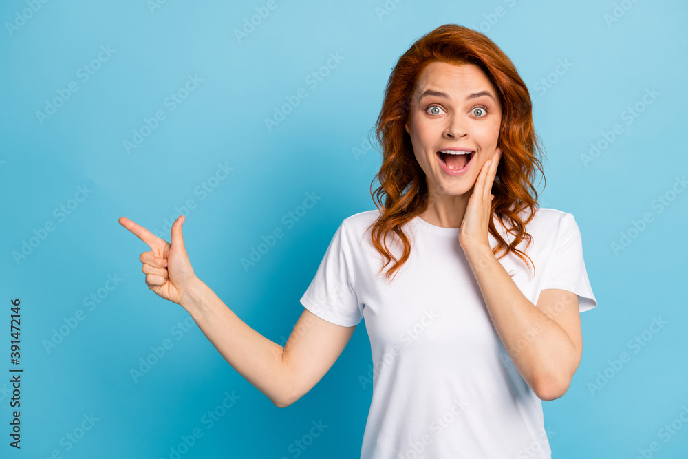 Photo portrait of shocked girl touching face cheek with hand pointing finger at blank space isolated on pastel blue colored background Photo portrait of shocked girl touching face cheek with hand pointing finger at blank space isolated on pastel blue colored background
