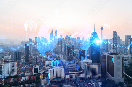 Hologram of social media icons over sunset panoramic cityscape of Kuala Lumpur, Malaysia, Asia. The concept of people connections in KL. Multi exposure.