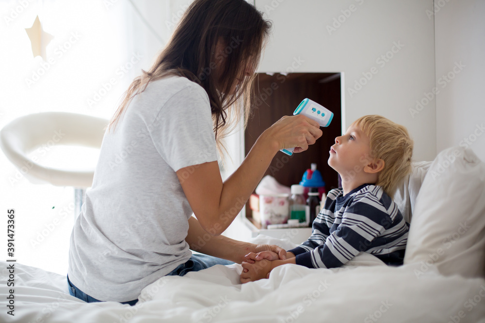 Mother, checking her son for fever with digital thermometer