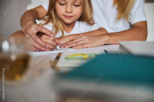 Woman with small female child while she is studying writing text on the notebook