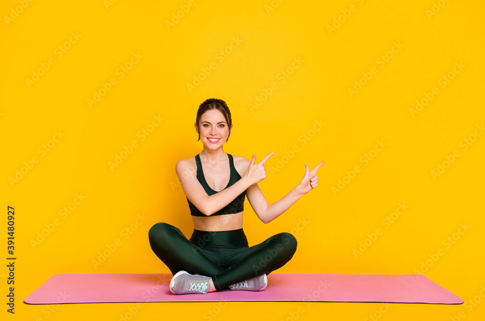 Portrait of attractive sportive cheery girl doing mat work demonstrating copy space isolated on bright yellow color background Portrait of attractive sportive cheery girl doing mat work demonstrating copy space isolated on bright yellow color background