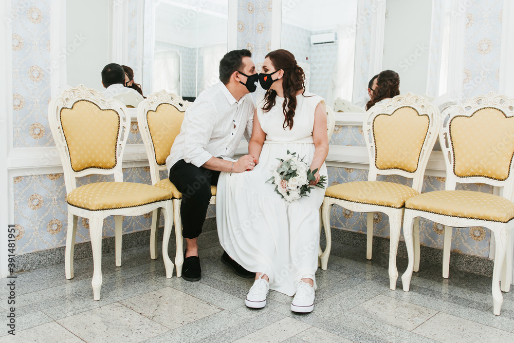 Wedding during the coronavirus period. Bride and groom in protective medical masks. Newlyweds and Covid-19 pandemic. Wedding during the coronavirus period. Bride and groom in protective medical masks. Newlyweds and Covid-19 pandemic.