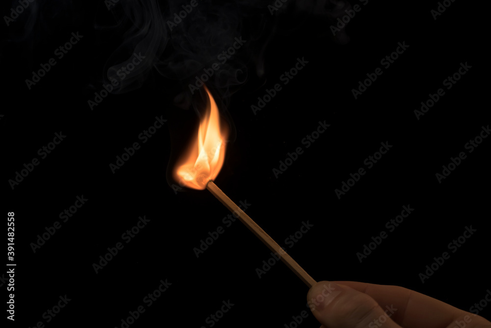 Hand holding a lighted match with fire flame and smoke on a black background. Hand holding a lighted match with fire flame and smoke on a black background.