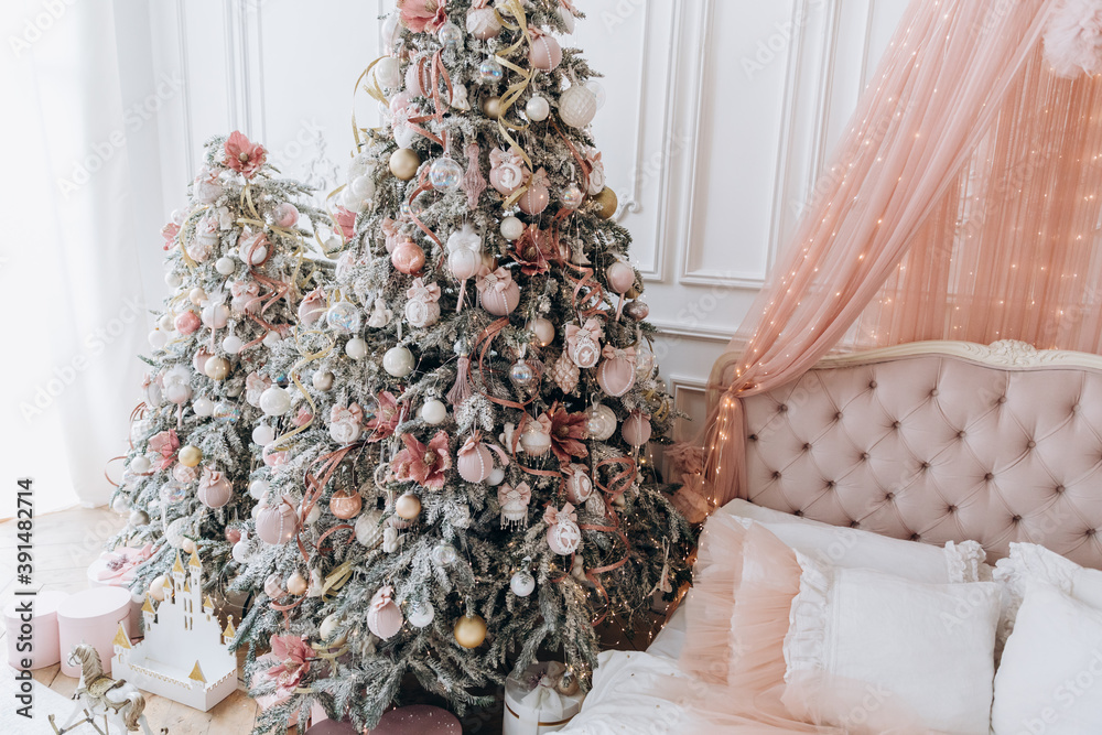 Beautiful room with new year decor with christmas tree and pink gifts near the bed and window Beautiful room with new year decor with christmas tree and pink gifts near the bed and window
