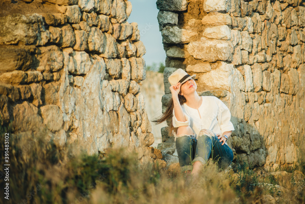 girl in a hat near a stone wall in summer