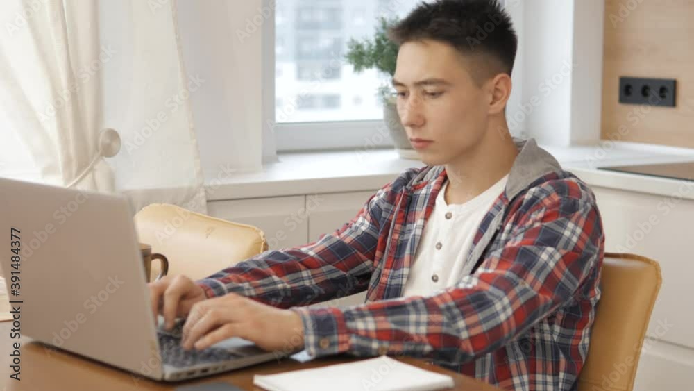 Caucasian guy studying online via internet on tablet while sitting at home morning and sunlight. Students using digital computer and write homework. Concept online learning at home